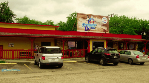 Exterior of Granny D's restaurant with a red roof, sign, and parked cars in front under a cloudy sky.