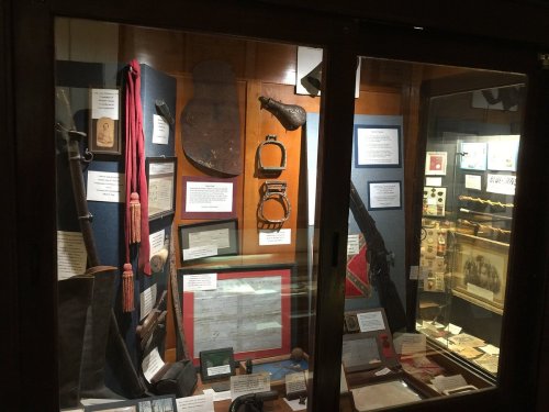 Display case featuring historical artifacts, including weapons, documents, and military gear.