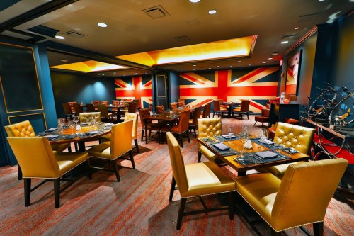 A stylish restaurant interior featuring yellow upholstered chairs and walls adorned with a large Union Jack design.