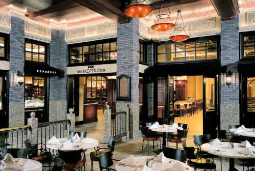 Elegant restaurant interior featuring brick walls, decorative lighting, and neatly set tables.