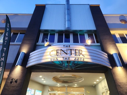 Exterior of "The Center for the Arts" building, featuring a marquee and modern architectural design at dusk.