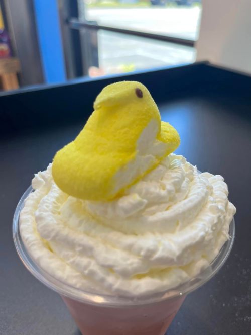 A dessert topped with whipped cream and a yellow marshmallow chick sitting on top.