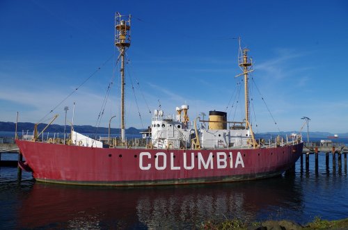 A red ship named "Columbia" docked by a pier under a clear blue sky.