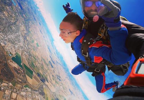 A person skydives with an instructor, capturing a thrilling aerial view of the landscape below.