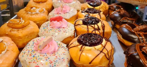 A variety of colorful donuts with sprinkles, frosting, and fruit toppings displayed on a tray.