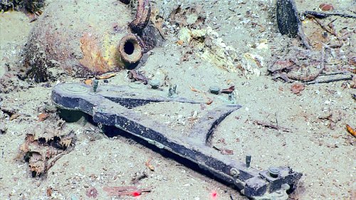 An underwater scene featuring a broken artifact and a clay pot, surrounded by sand and debris.