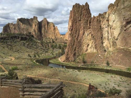 A scenic view of rugged rock formations and a winding river surrounded by greenery under a cloudy sky.