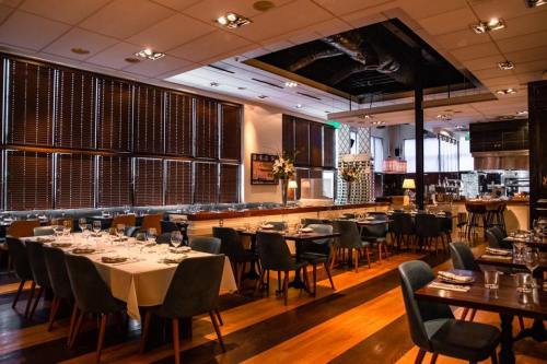 Elegant restaurant interior with wooden floors, tables set for dining, and large windows with blinds.