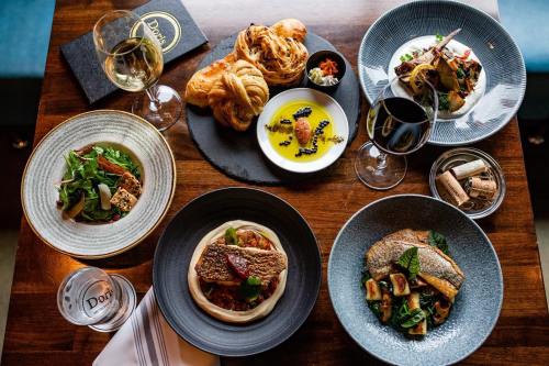 A table set with gourmet dishes, wine glasses, and pastries, showcasing a variety of beautifully plated meals.
