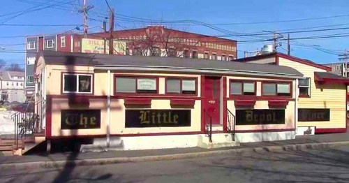 A colorful building with a sign reading "The Little Depot" in a small town setting, surrounded by power lines.