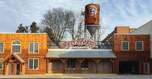 Exterior of Copper Barrel Distillery featuring wooden architecture and a large water tower with a logo.
