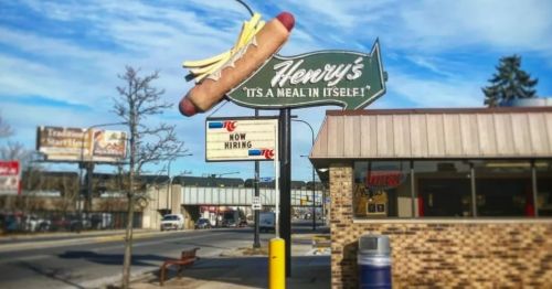 Sign for Henry's restaurant featuring a hot dog and fries, with a "Now Hiring" message below.