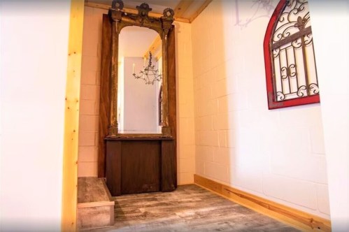 A cozy entryway featuring a vintage mirror, wooden accents, and a small bench on a wooden floor.