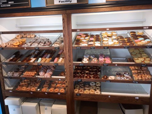 A display case filled with a variety of colorful donuts, including glazed, frosted, and filled options.