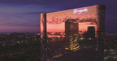 The Borgata hotel reflects a colorful sunset, showcasing its modern architecture against a twilight sky.