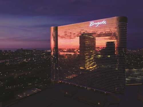 Aerial view of the Borgata Hotel at dusk, reflecting colorful lights against a twilight sky.