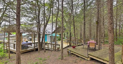 A wooden deck surrounded by trees, featuring outdoor seating and a cozy cabin in a serene, natural setting.