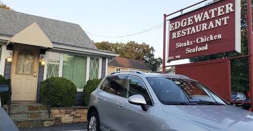 Exterior of Edgewater Restaurant with a sign, featuring a house and a parked silver SUV in front.