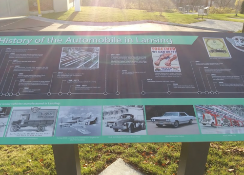 A display board detailing the history of automobiles in Lansing, featuring timelines and images of classic vehicles.