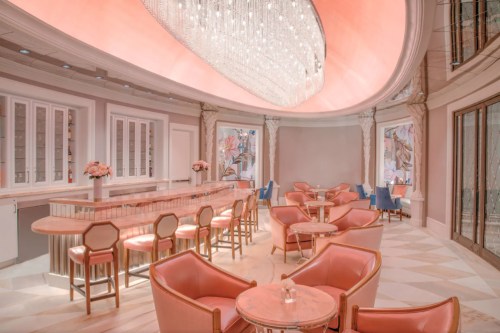 Elegant café interior with pink decor, a chandelier, and stylish seating arrangements.