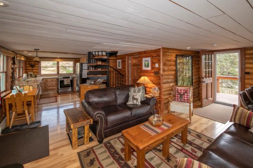 Cozy log cabin interior featuring a living area, kitchen, and dining space with wooden accents and natural light.