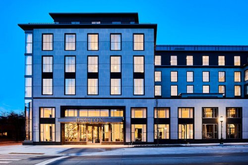 Modern hotel exterior at dusk, featuring large windows and a welcoming entrance.