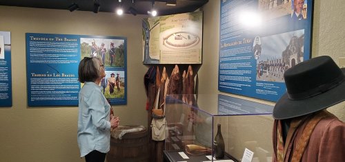 A visitor examines historical displays in a museum, featuring artifacts and information about Fort Verdugo and local history.