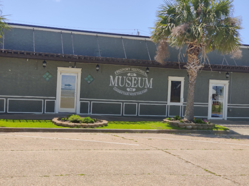 Exterior of the Freeport Historical Museum, featuring a sign and palm trees in front.
