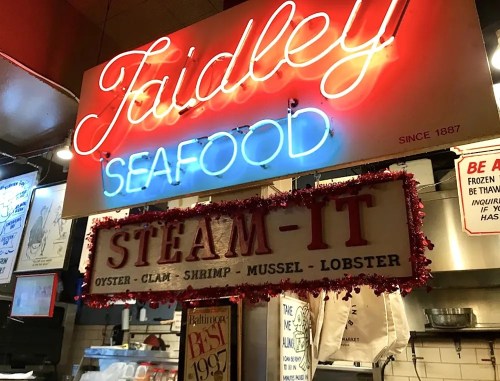 Neon sign for "Faidey Seafood" with a decorative "Steam-It" sign listing seafood options like oysters and shrimp.