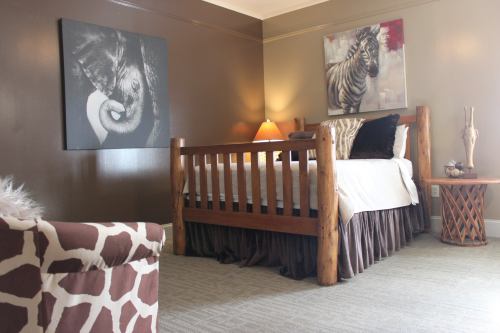 Cozy bedroom featuring a wooden bed, animal-themed decor, and a giraffe-patterned chair against a brown wall.