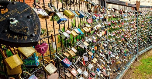 A colorful display of various padlocks attached to a metal fence, symbolizing love and commitment.