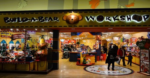 Entrance to a Build-A-Bear Workshop, featuring colorful displays of stuffed animals and toys inside.