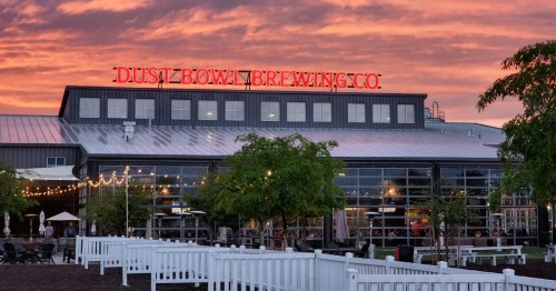 Dust Bowl Brewing Co. building at sunset, featuring large neon signage and outdoor seating area.