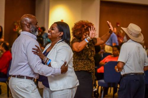 A lively gathering with people dancing and enjoying themselves in a spacious venue.