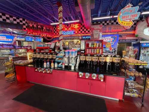 A colorful diner counter filled with various drink dispensers, snacks, and neon signs in a retro-themed setting.