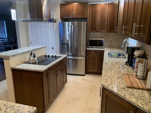 Modern kitchen with granite countertops, stainless steel appliances, and wooden cabinets, featuring a stove and sink.