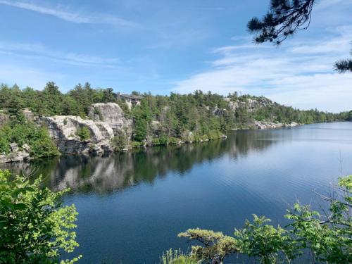 A serene lake surrounded by rocky cliffs and lush greenery under a clear blue sky.