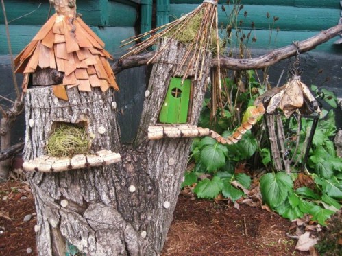 Whimsical tree houses made from wood and natural materials, featuring green doors and a lantern, surrounded by greenery.
