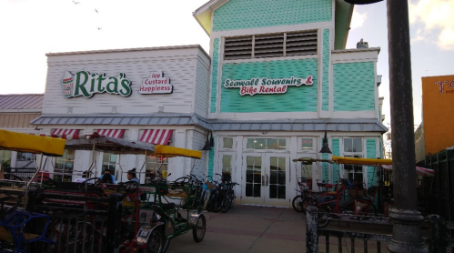 Exterior of a colorful building featuring "Rita's Ice Custard Happiness" and "Seaweed Sourcing & Bike Rental" signs. Bikes parked outside.