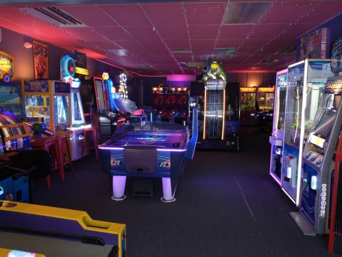 A vibrant arcade filled with various gaming machines and colorful lights, creating a fun atmosphere.