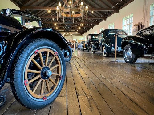 A vintage car exhibit featuring classic cars lined up in a spacious, well-lit wooden gallery.