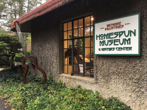Exterior of the Homespun Museum and Visitors Center, featuring a large guitar sculpture and a welcoming sign.