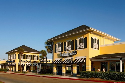 Two retail buildings with yellow exteriors and black-and-white striped awnings, set against a clear blue sky.