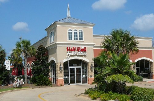 Exterior of Half Shell Oyster House, featuring a peaked roof and palm trees under a blue sky.