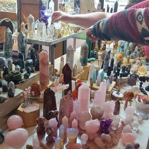 A display of various crystals and gemstones in different shapes and colors, arranged on tables.