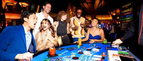 A group of friends joyfully celebrating at a casino table, with drinks and cards in a vibrant atmosphere.