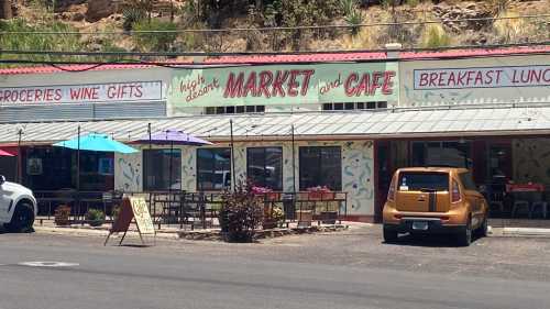 A colorful market and café with outdoor seating, umbrellas, and a sign reading "High Desert Market and Café."