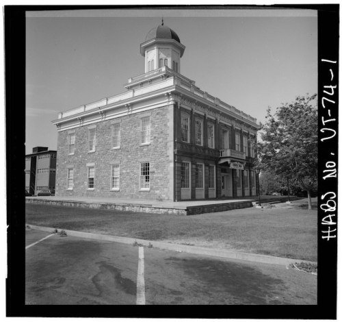 Historic stone building with a dome, featuring large windows and a grassy area, captured in black and white.