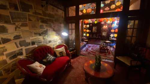 Cozy vintage room with a red sofa, colorful lanterns, and a wall adorned with historical photographs.