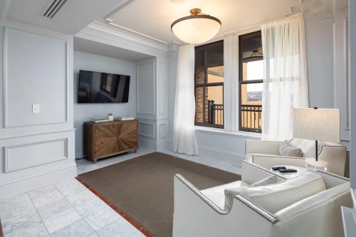 Cozy living space with a TV, light-colored furniture, and large windows letting in natural light.